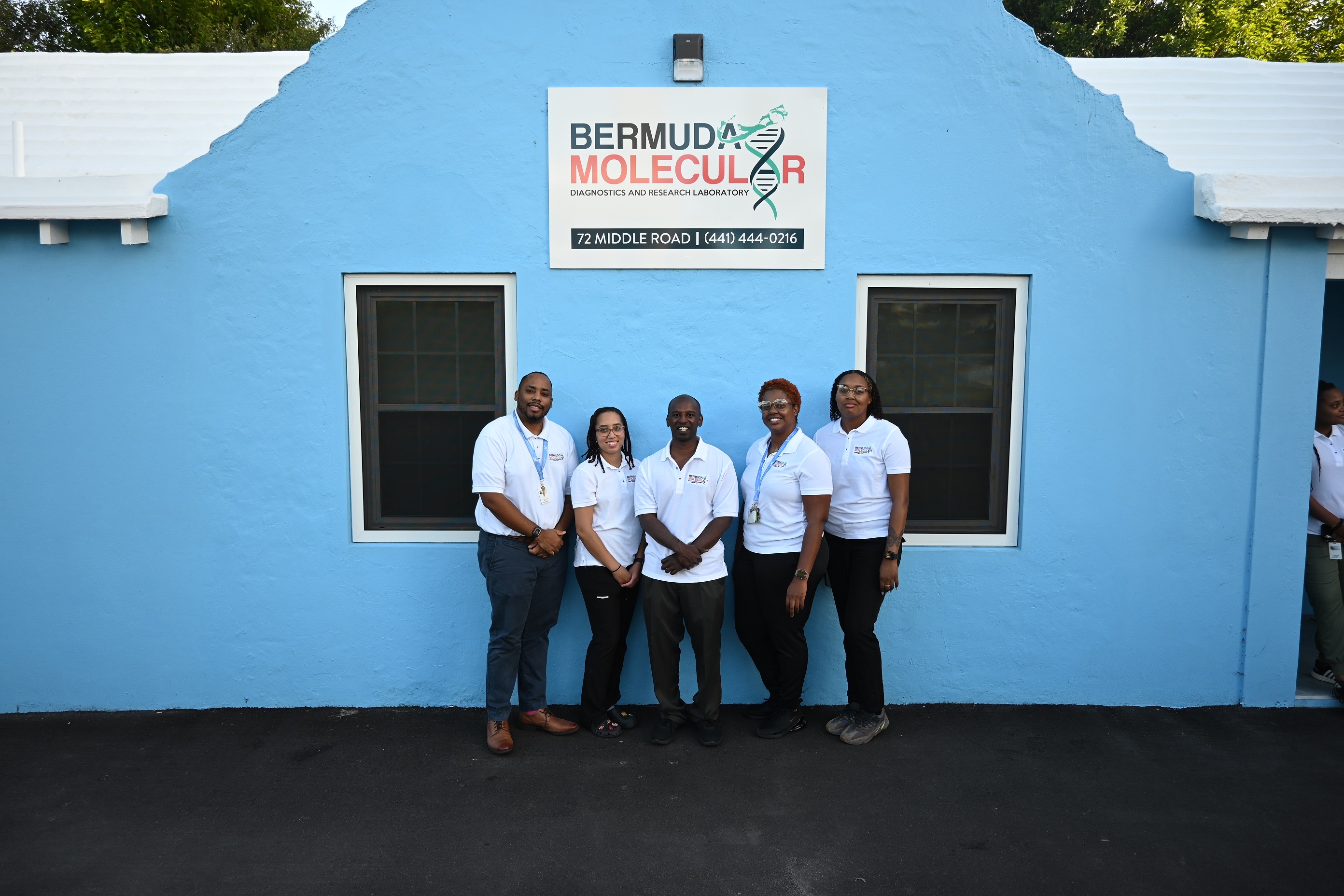 a group of people standing together in front of a blue building in Bermuda