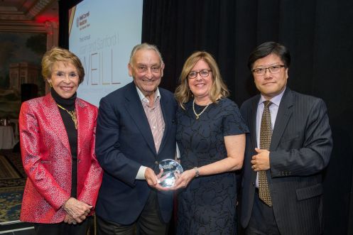 Four people in a group, with the middle two holding an award