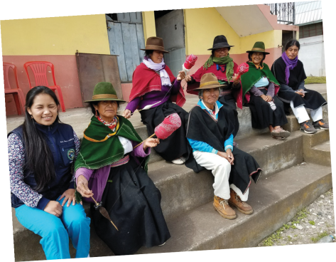 Women spinning wool yarn while awaiting an exam at an off-site clinic (an employee is at left in scrubs). Photo provided.