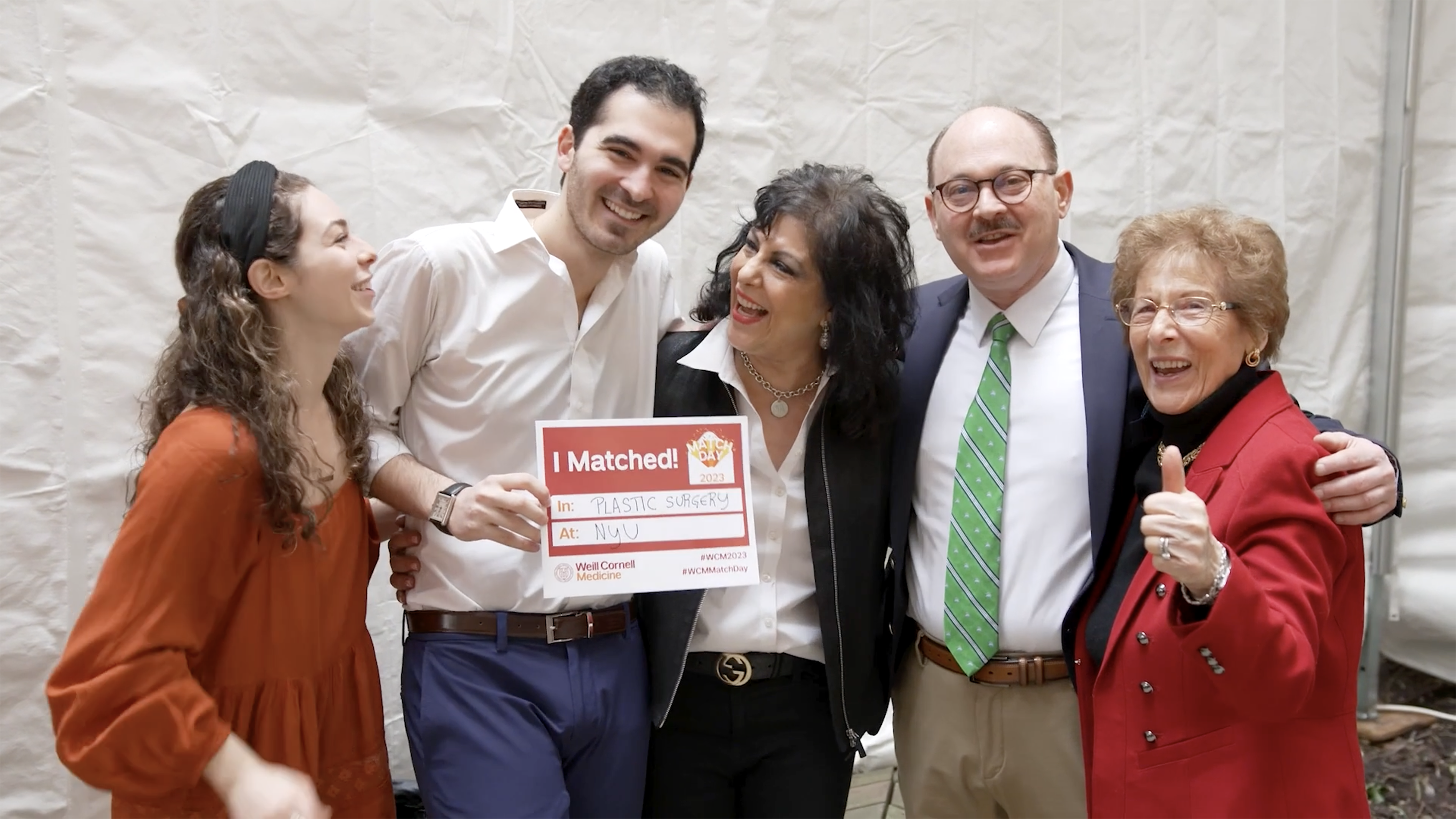 a male medical student flanked by his family while celebrating good news.